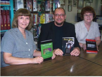 Author and Ashland native Thomas M. Malafarina sits with Ashland Public Library librarians Rene Hardnock left and Ann Helwig. They are holding the three books he authored, which were donated to the library Friday.